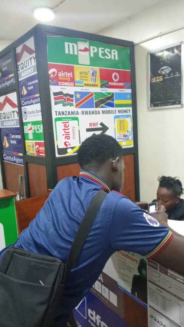 Customer at the mobile money counter, with MTN, Airtel and M-PESA signage